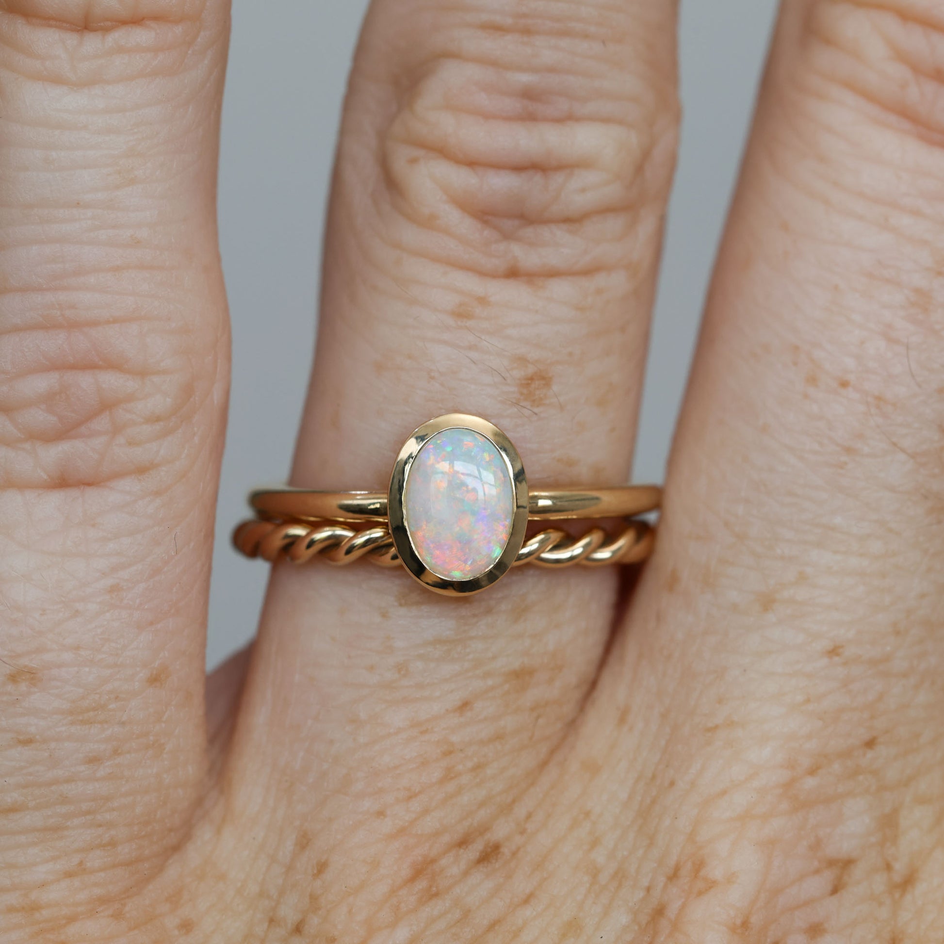 0.43ct opal bezel ring on hand stacked with another ring