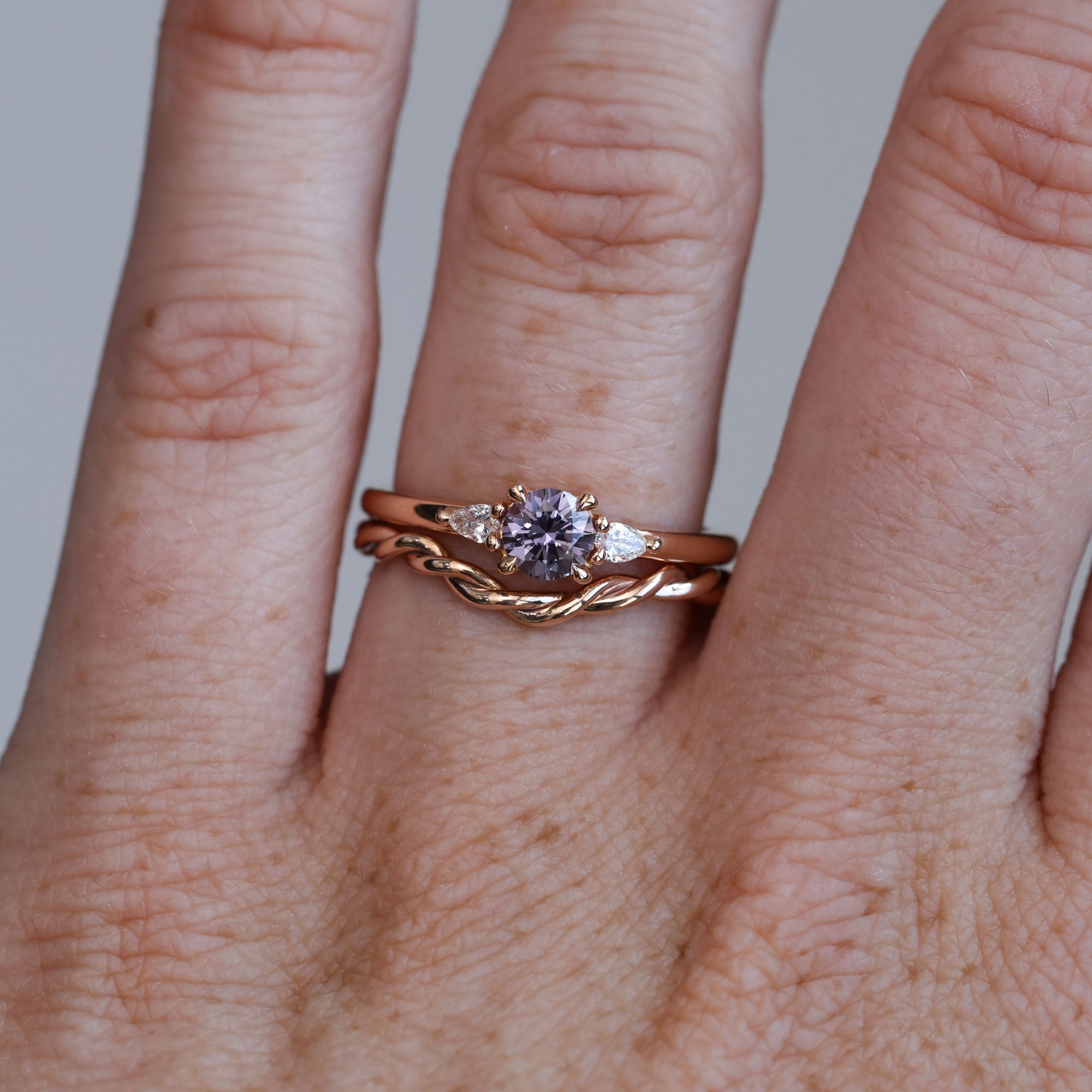 0.47ct Purple Montana Sapphire trilogy engagement ring on hand with wedding band