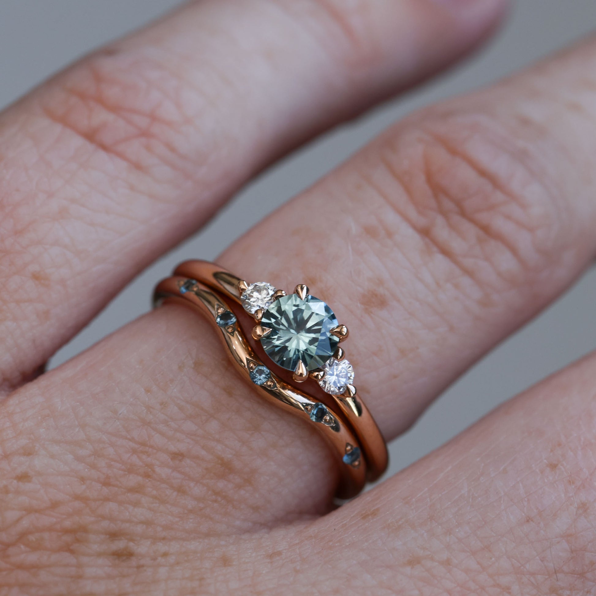 0.58ct Montana Sapphire trilogy engagement ring on hand and wedding band