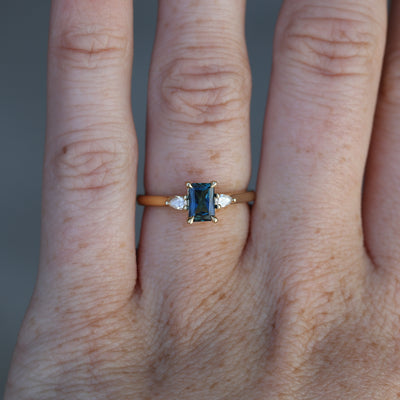 0.66ct Emerald cut australian sapphire trilogy engagement ring on hand