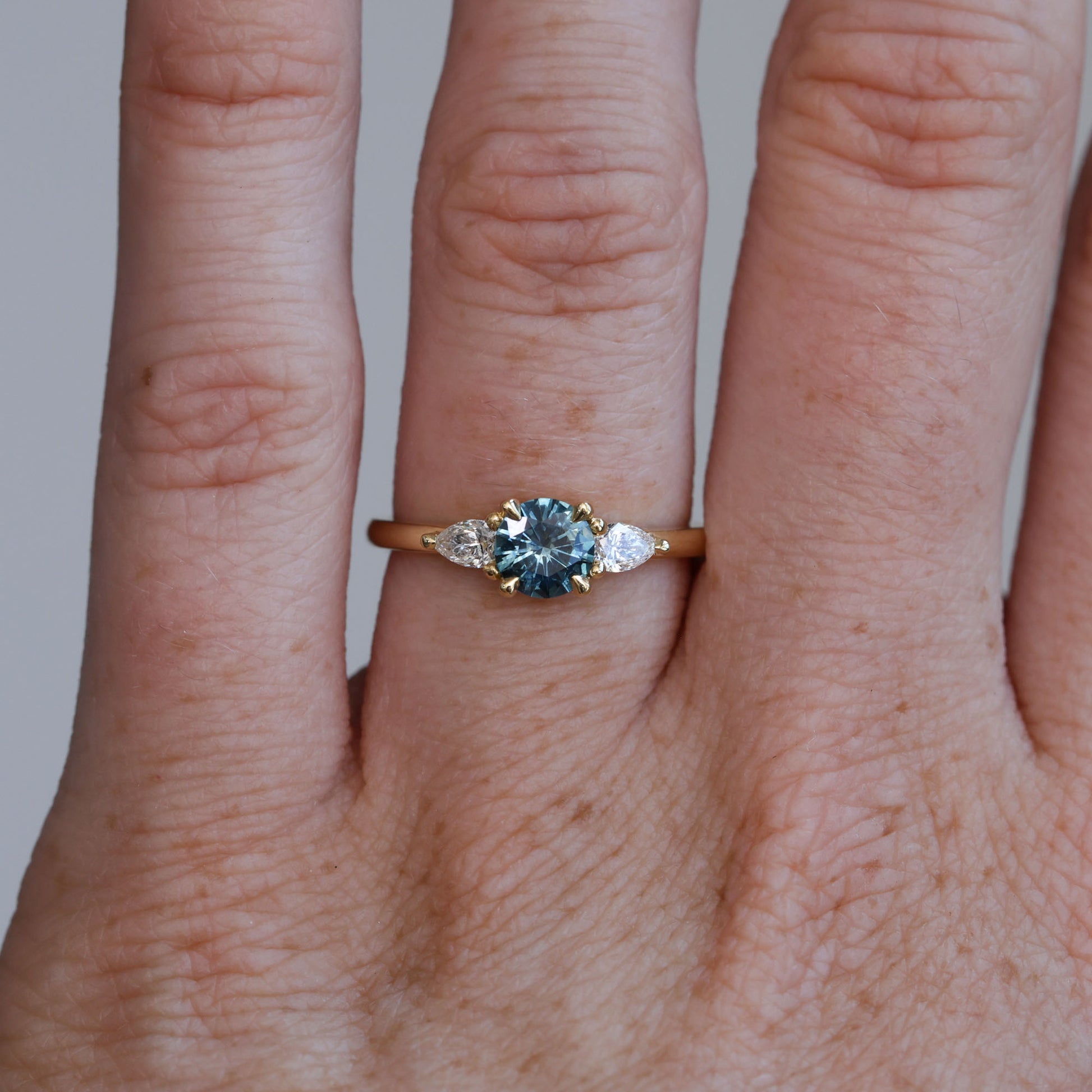 0.67ct Montana Sapphire and diamond May trilogy engagement ring on hand