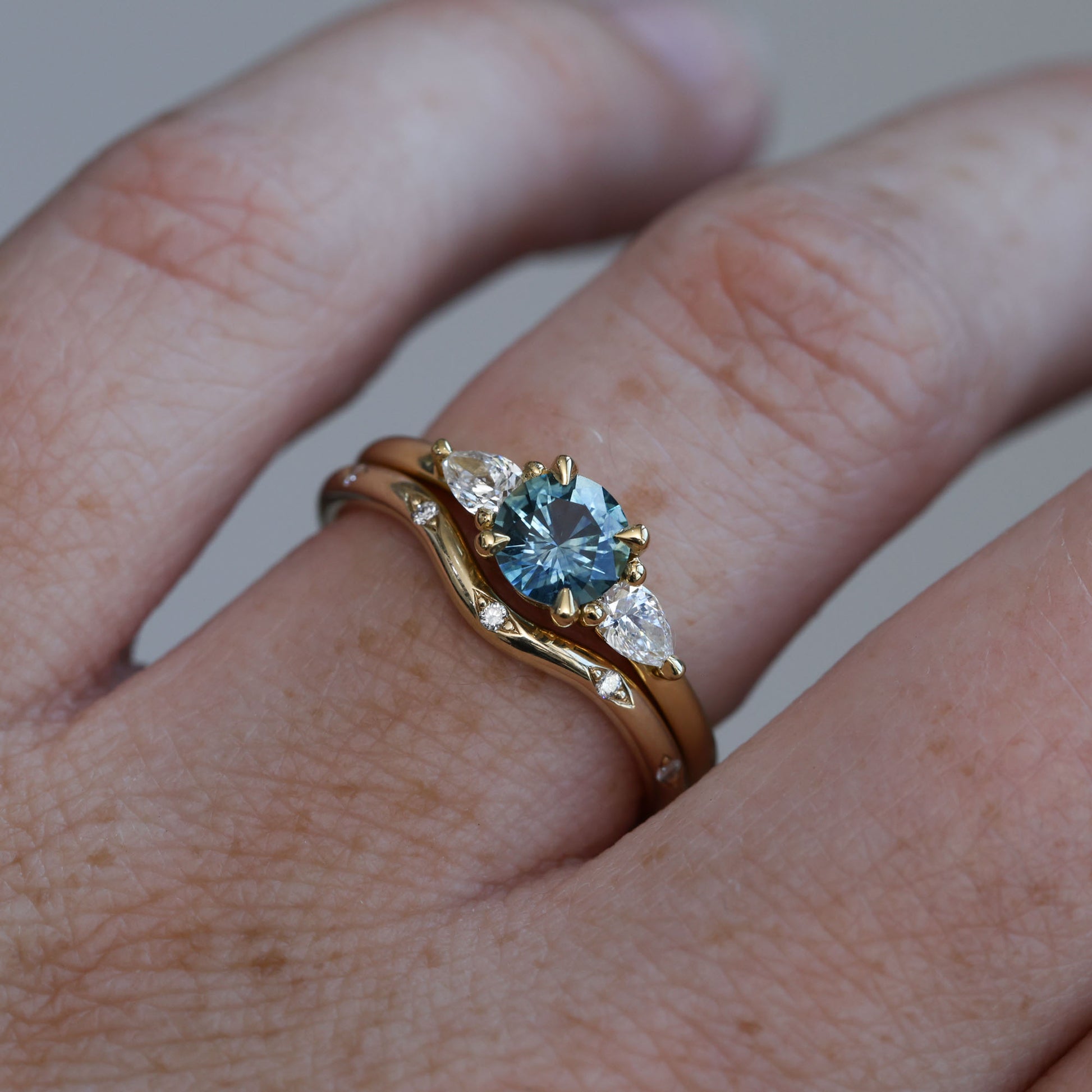 0.67ct Montana Sapphire and diamond May trilogy engagement ring on hand