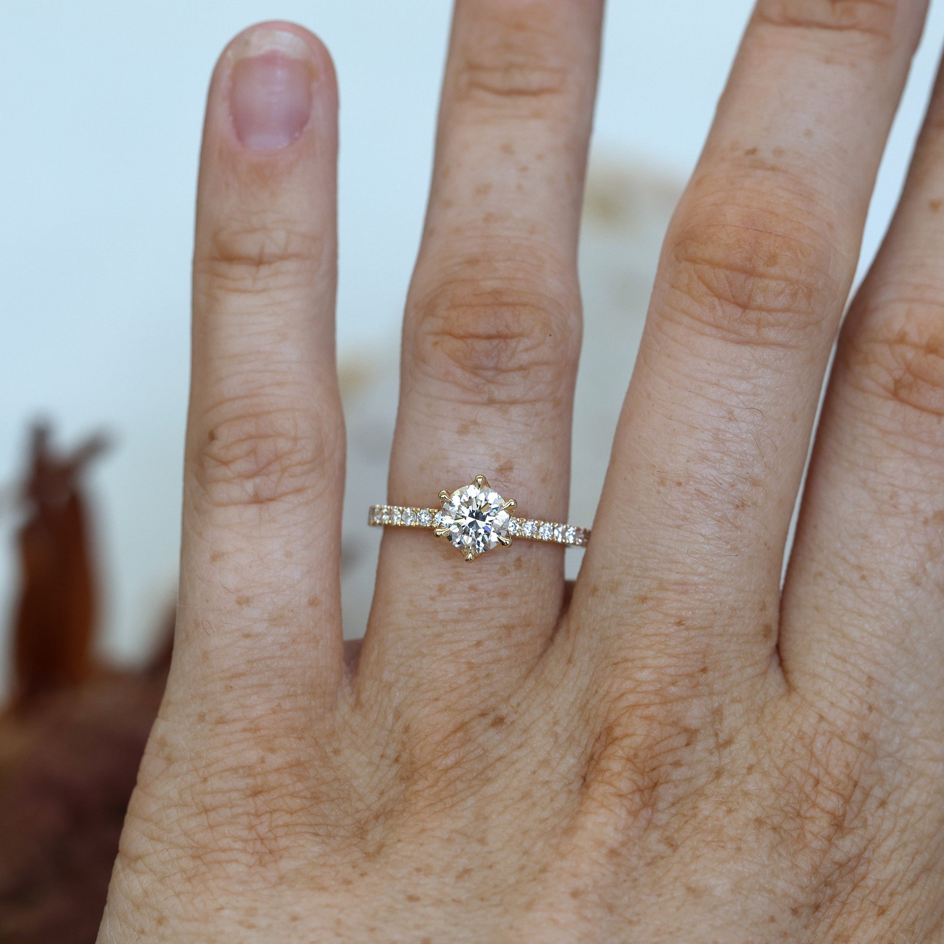 0.82ct round cut diamond engagement ring with diamond pave band on hand