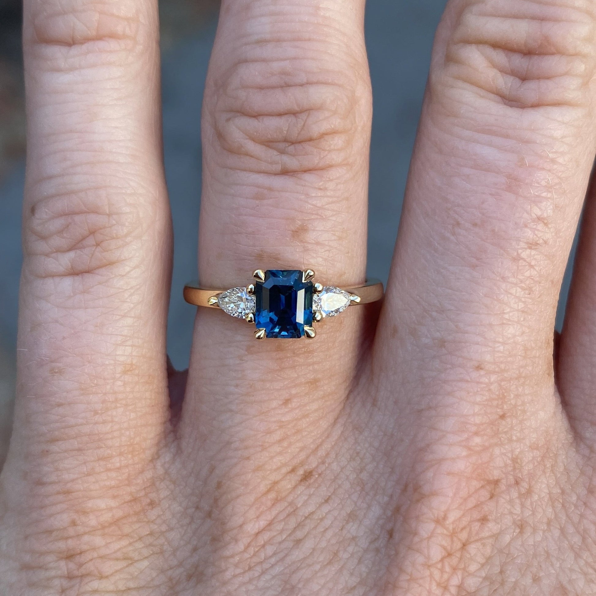 1.13ct emerald cut Madagascan sapphire trilogy engagement ring on hand