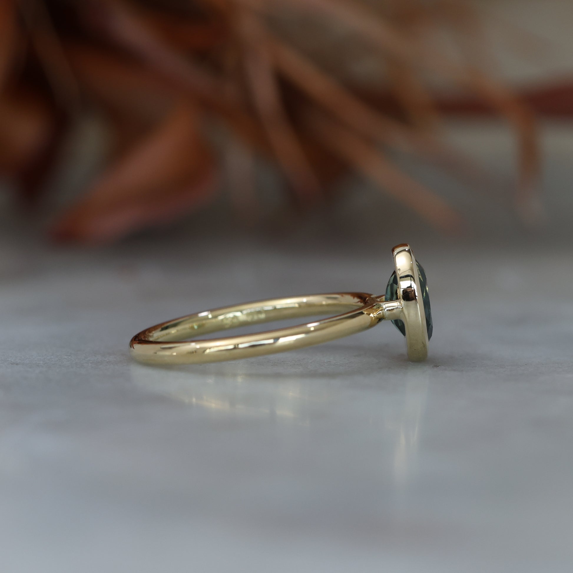 Bezel set oval cut Australian parti sapphire engagement ring in 18ct yellow gold  side view