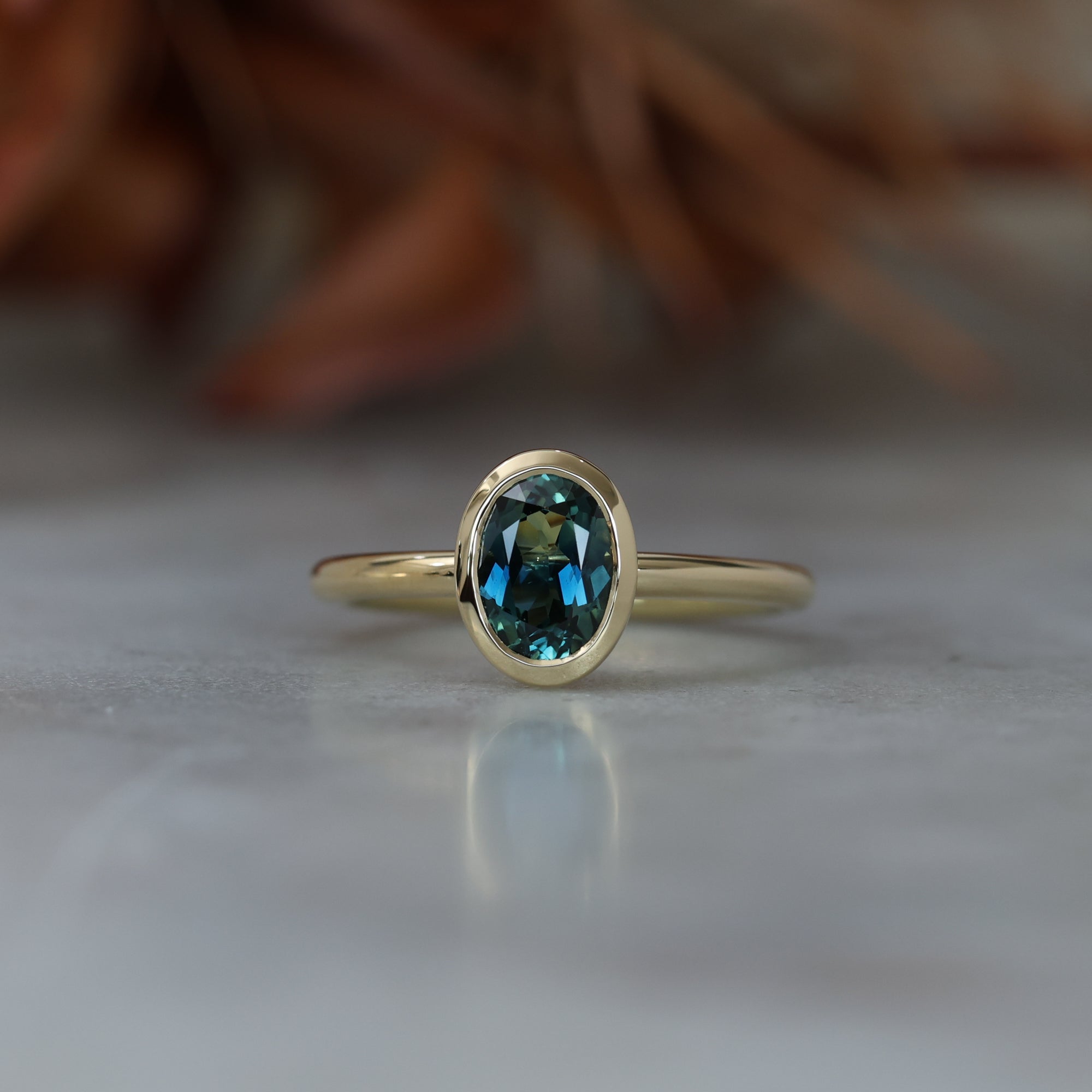 Bezel set oval cut Australian parti sapphire engagement ring in 18ct yellow gold