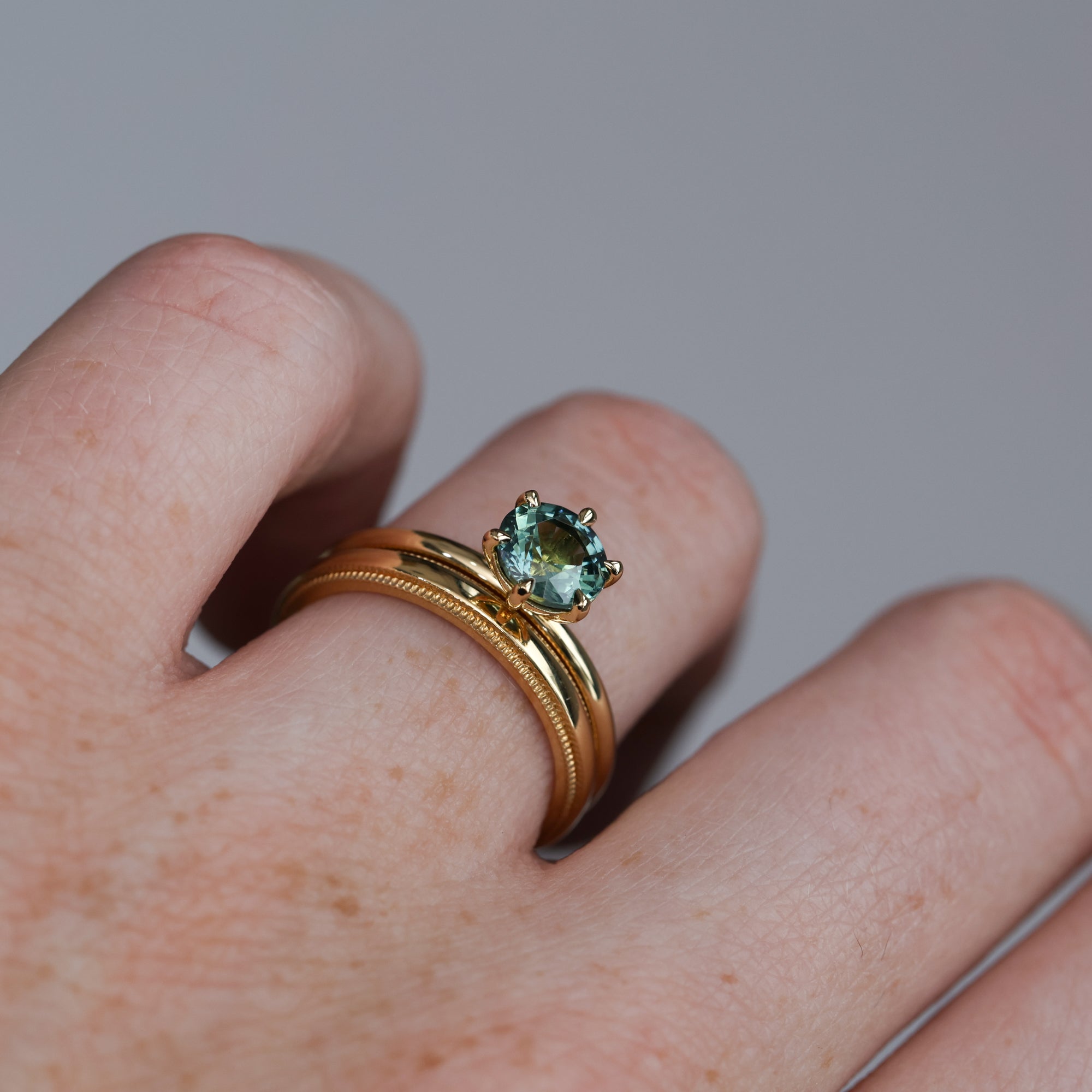 1.20ct round cut madagascan sapphire solitaire engagement ring on hand with millgrain wedding band