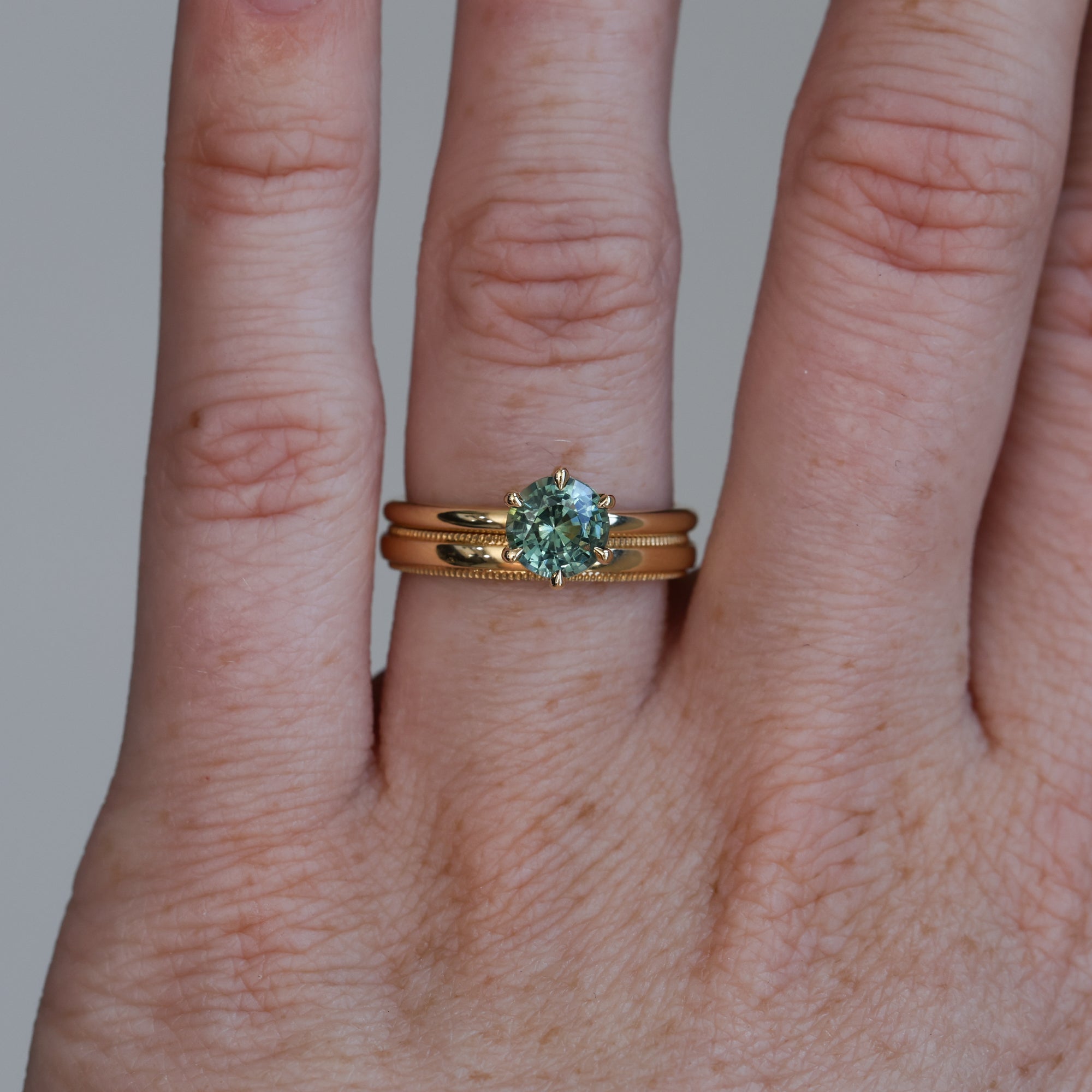 1.20ct round cut madagascan sapphire solitaire engagement ring on hand with wedding band