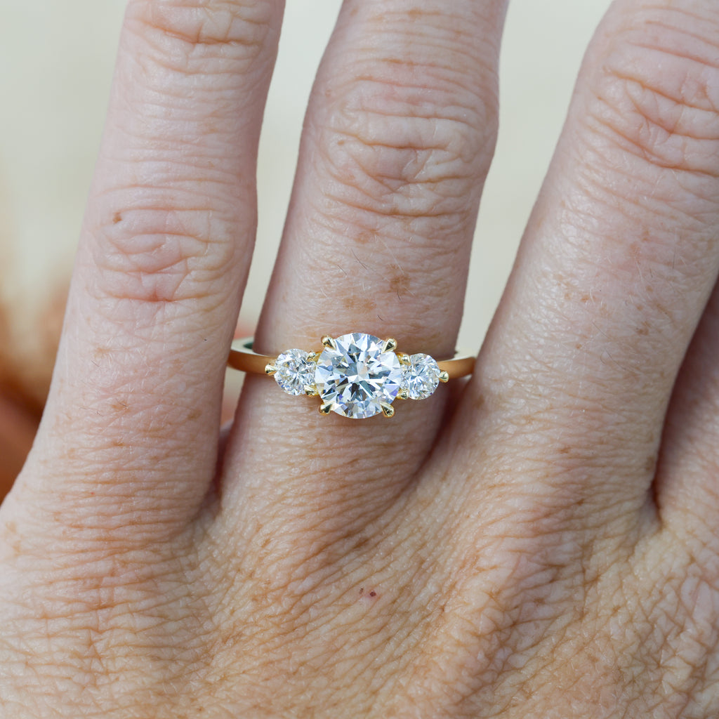 diamond round cut trilogy engagement ring yellow gold on hand