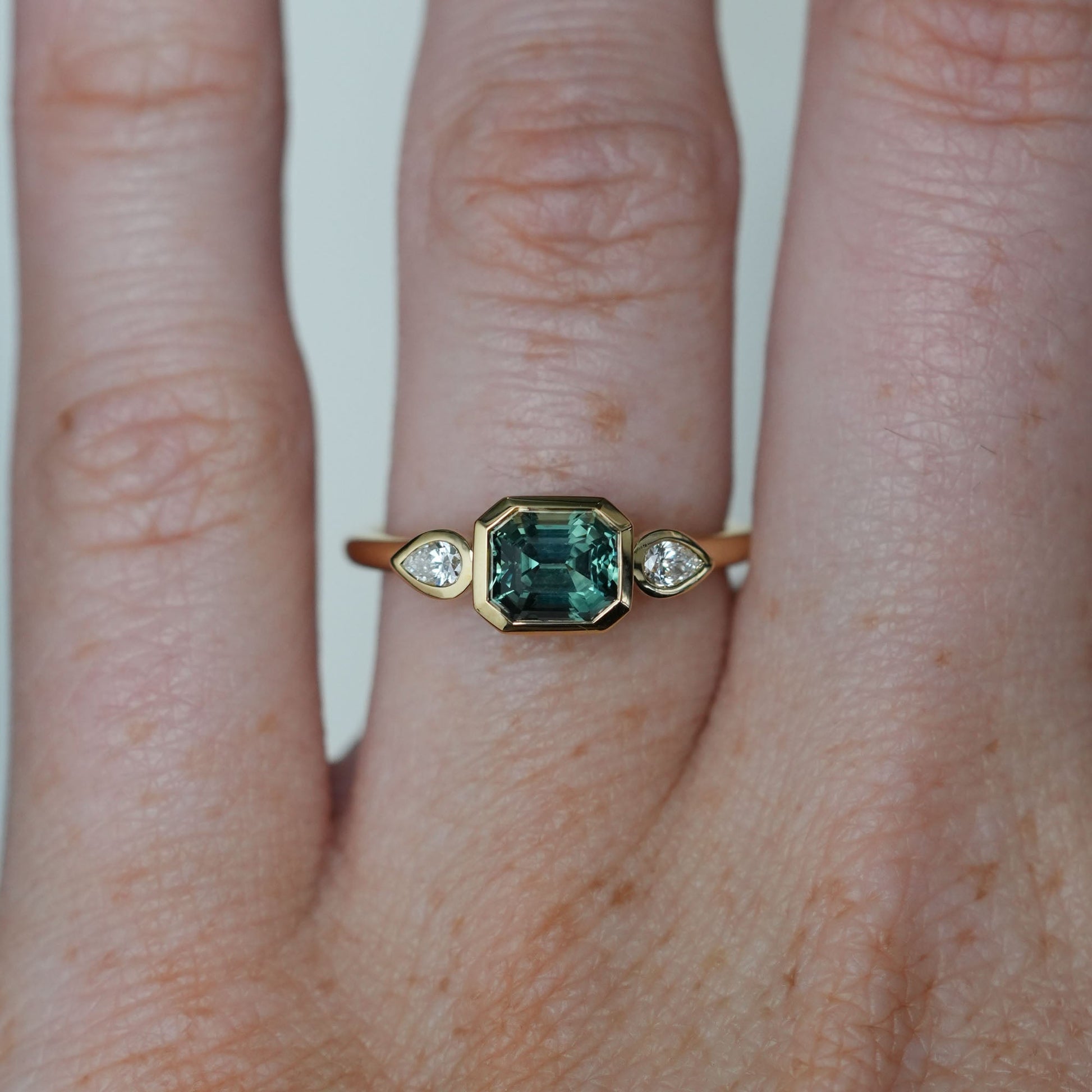 1.51ct Madagascan Sapphire Bezel trilogy engagement ring on hand