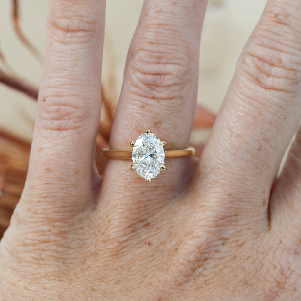 2ct oval cut diamond solitaire engagement ring on hand