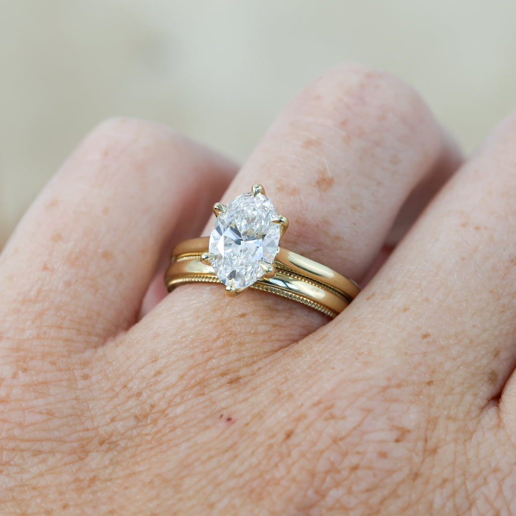 2ct oval cut diamond solitaire engagement ring on hand with wedding band