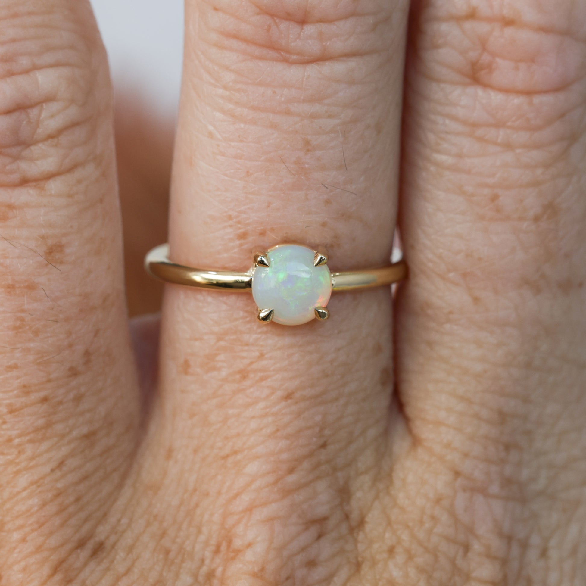 6mm round cut Australian opal ring yellow gold on hand