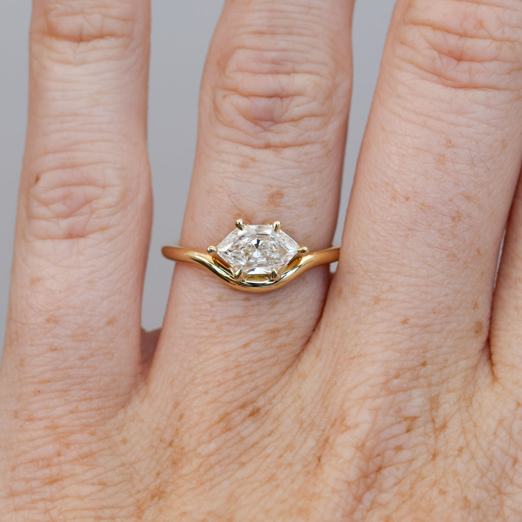 eden 1.00ct elongated hexagon diamond on curved yellow gold band on hand 