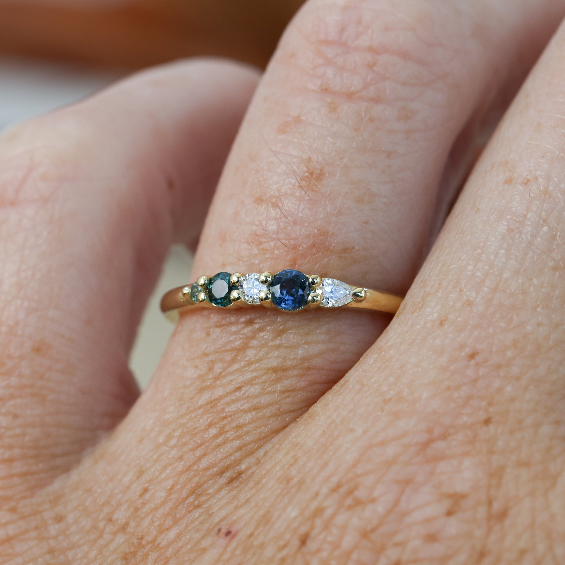 Blue and green Australian Sapphire and diamond fine jewellery ring yellow gold on hand close up
