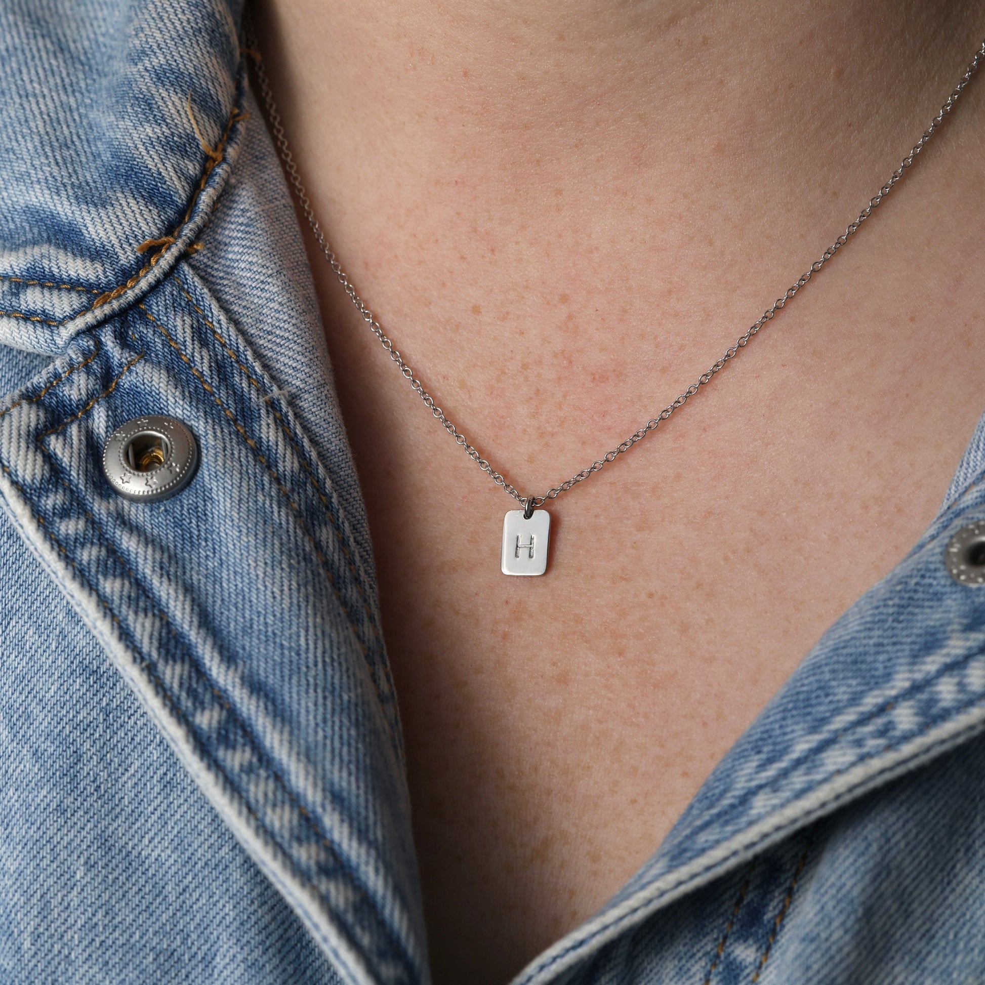 Initial tablet necklace on neck