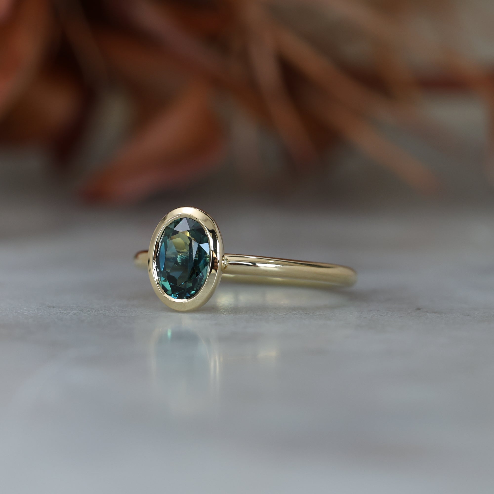 Bezel set oval cut Australian parti sapphire engagement ring in 18ct yellow gold side view