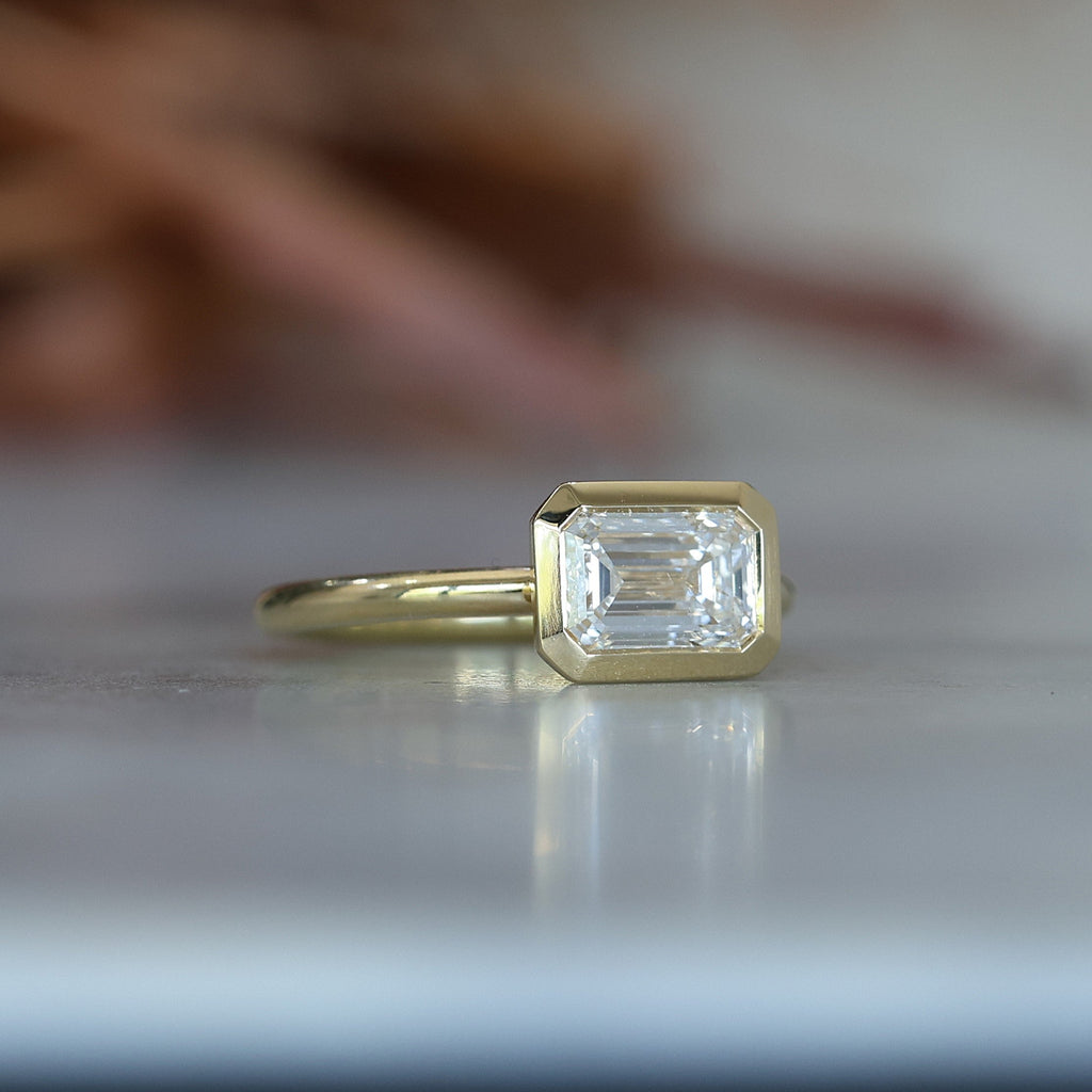 emerald cut diamond bezel set engagement ring