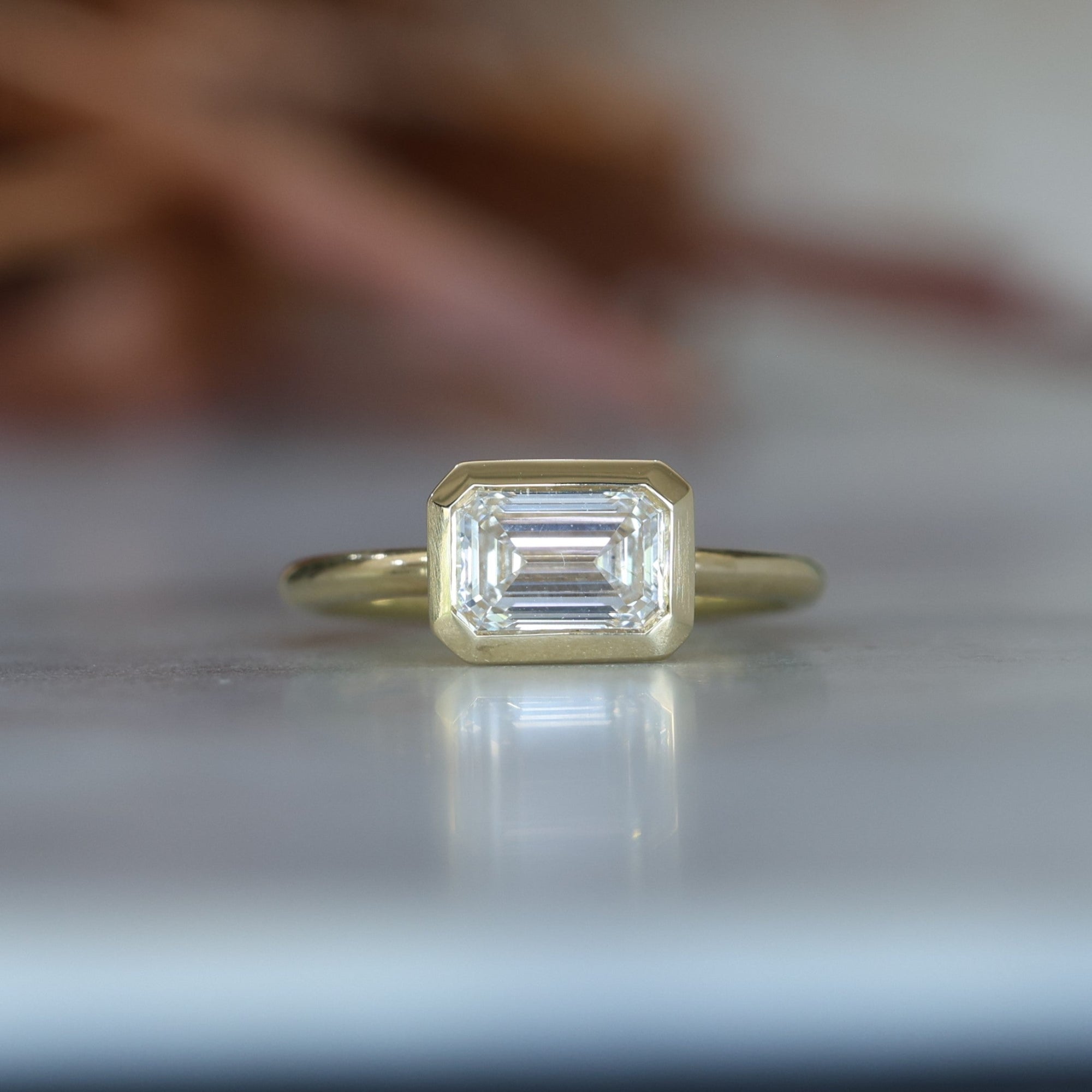 emerald cut diamond bezel set engagement ring
