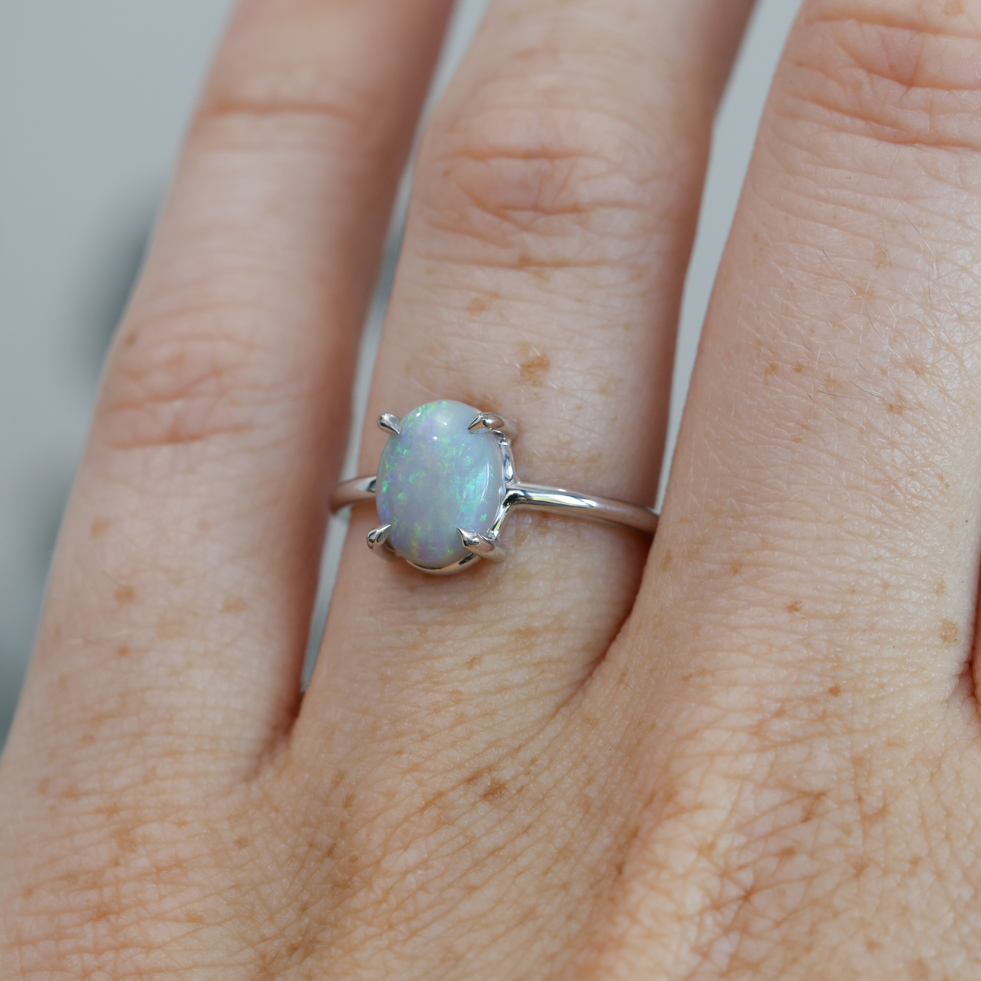 oval cut Australian opal ring on hand in white gold