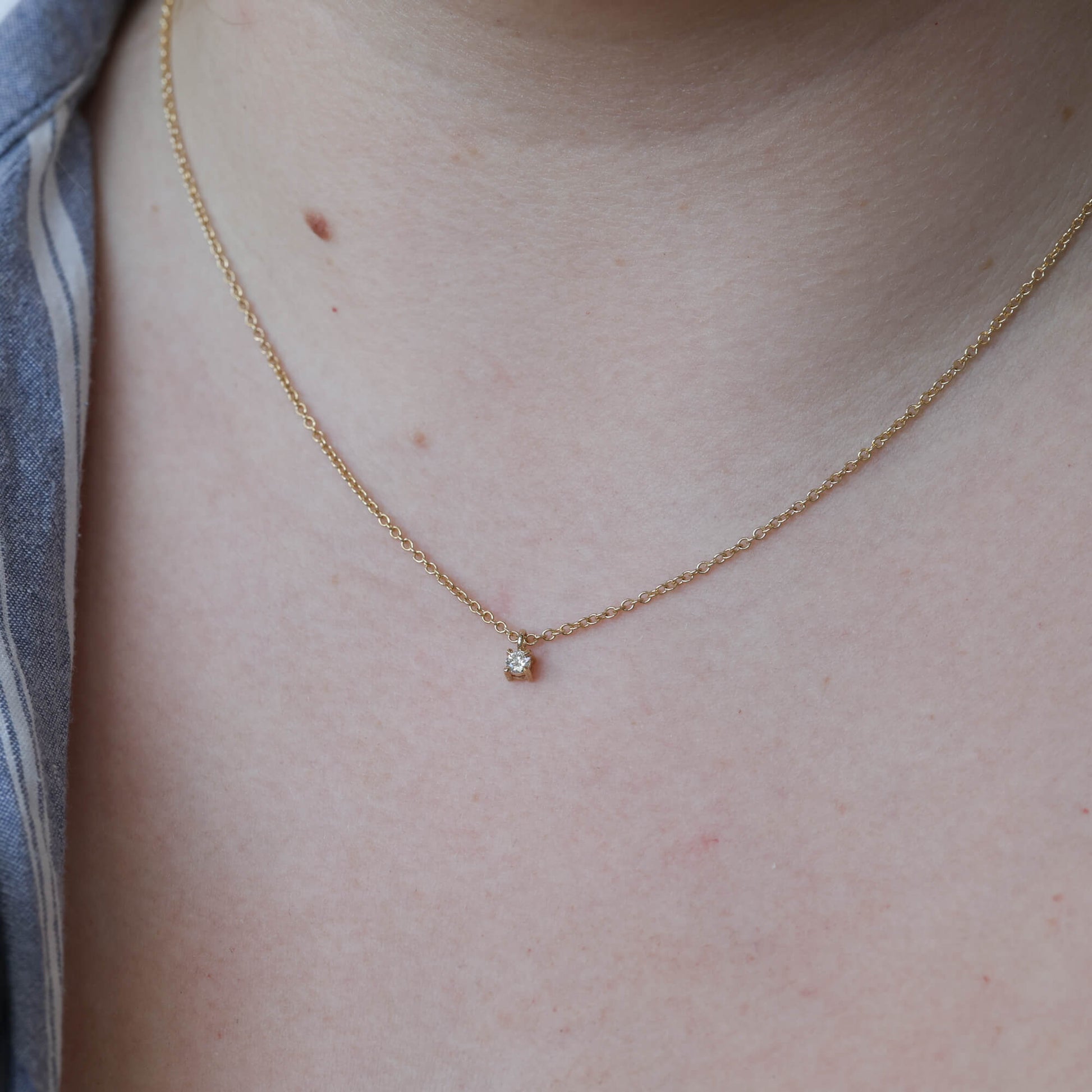 petite round cut diamond necklace on neck