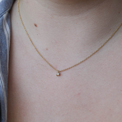 petite round cut diamond necklace on neck
