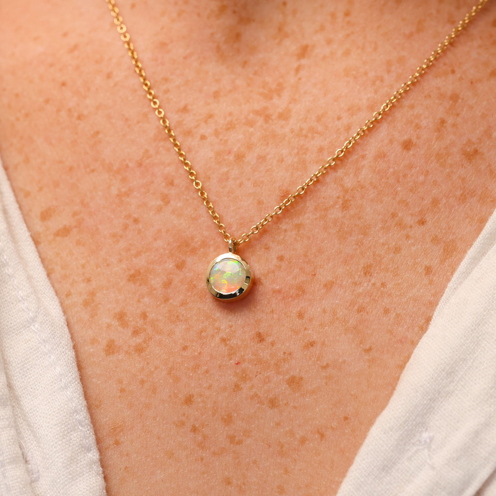 round cut opal set in a full 9ct yellow gold bezel east west setting